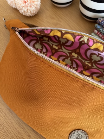 Bolsa de tecido laranja com interior estampado floral e fecho metálico aberto