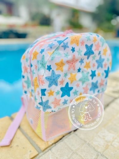 Mochila infantil colorida com estrelas ao lado de piscina