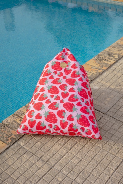 Almofada triangular com padrão de morangos vermelhos junto à piscina