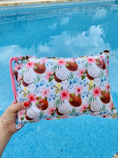 Bolsa pequena com estampa de cocos e flores tropicais junto a uma piscina