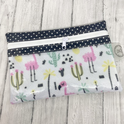 Estojo estampado com flamingos, cactos e flores, fecho branco e padrão de bolinhas azul escuro