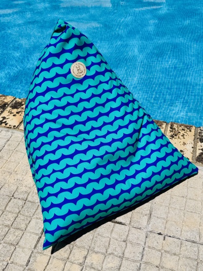 Pufe triangular azul com padrão de ondas junto a piscina
