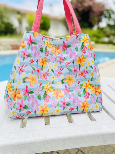 Saco floral colorido com alças cor-de-rosa junto a piscina