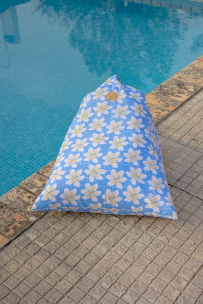 Almofada triangular azul com flores brancas e amarelas junto a piscina