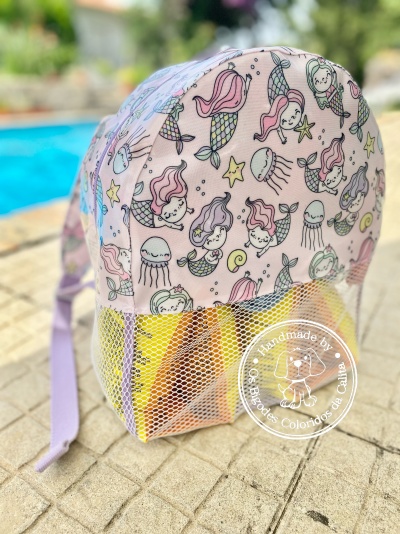 Mochila infantil rosa com padrão de sereias e bolso de rede branco