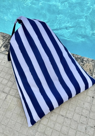 Toalha de praia listrada azul e branca junto à piscina