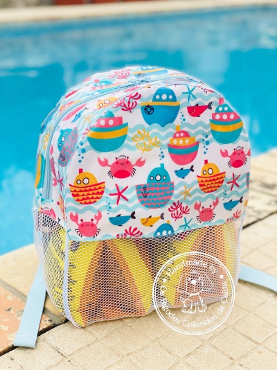 Mochila infantil colorida junto a piscina com motivos marítimos