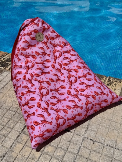 Pufe triangular rosa com lagostas vermelhas junto a piscina