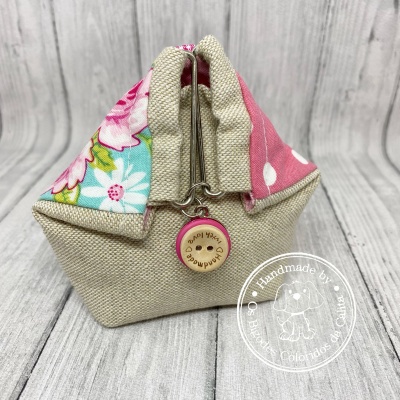 Bolsa pequena em tecido bege com detalhes em rosa e azul floral, fecho metálico e botão em madeira com texto gravado