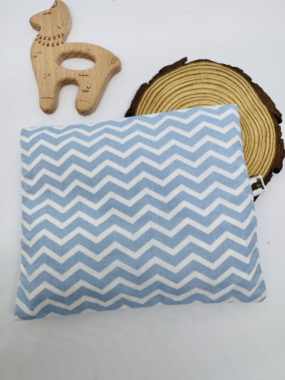 Almofada azul e branca com padrão zig-zag ao lado de brinquedo de madeira e peça de madeira redonda.