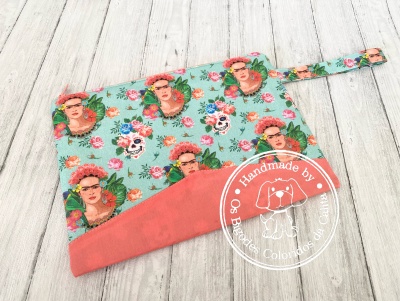 Necessaire colorida com padrão de rostos femininos e caveiras sobre madeira clara