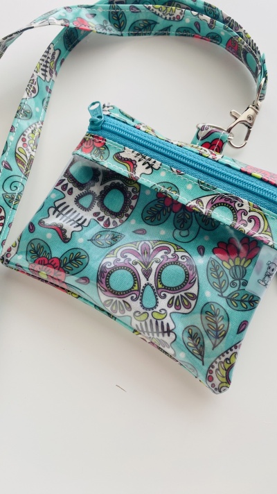 Bolsa pequena com padrão de caveiras coloridas em fundo azul-turquesa