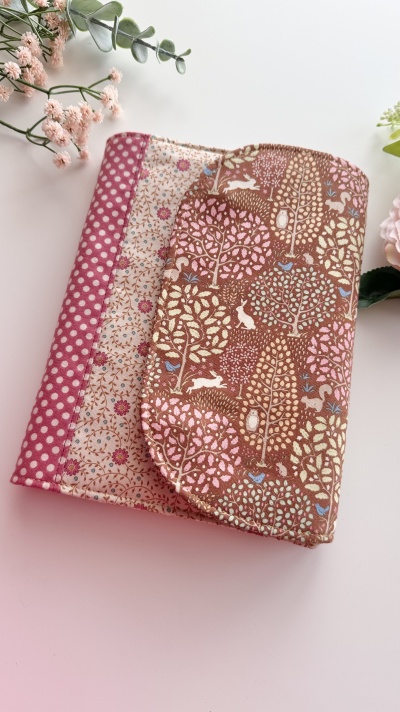 Estojo ou bolsa de tecido com padrões florais e de bolinhas em tons castanho, rosa e bege