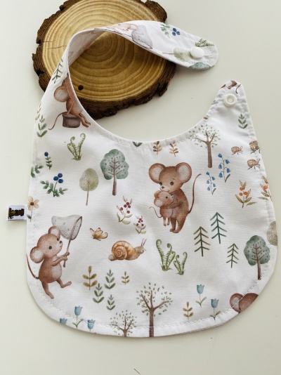 Babete estampado com ratos e natureza sobre fundo branco.
