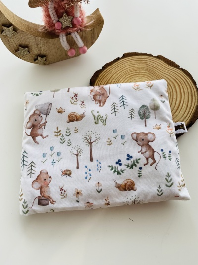Almofada retangular com padrão de ratos e caracóis em fundo branco, com decoração em madeira ao lado