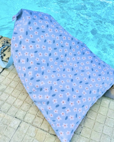Pufe azul claro com padrão floral junto à piscina
