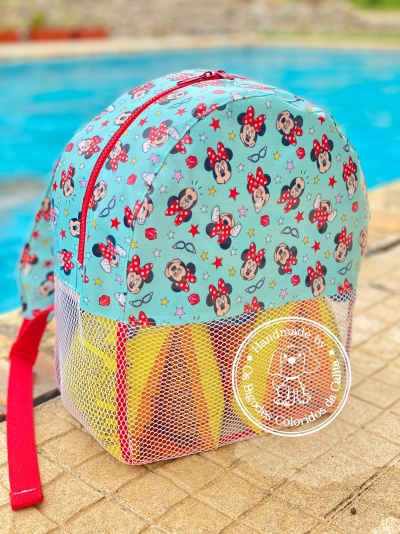 mochila infantil azul com padrão da Minnie e rede branca junto a piscina