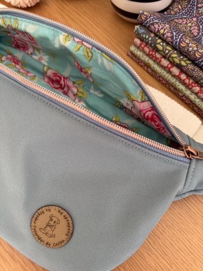 Bolsa pochete azul com interior floral e etiqueta de couro