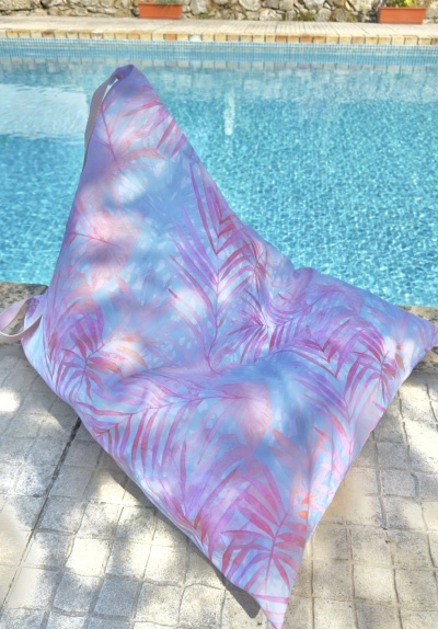 Puff triangular estampado cor-de-rosa e lilás ao lado de piscina