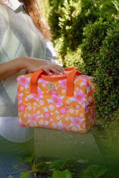 Mala térmica cor de laranja com padrão floral e alças laranja ao ar livre