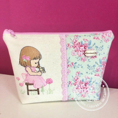 Necessaire de tecido floral com bordado de menina segurando passarinho e fecho rosa