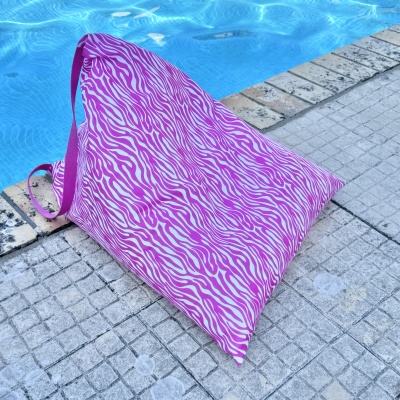 Mala tipo saco rosa com padrão de riscas zebras perto de piscina