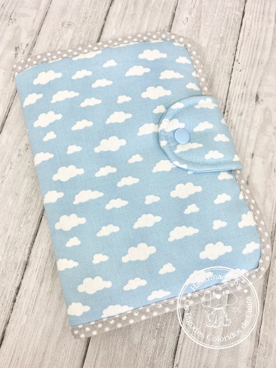 Capa de tecido azul com nuvens e bordas cinzentas com bolinhas