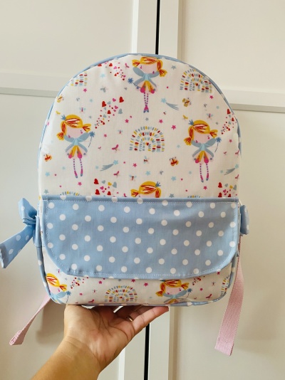 Mochila infantil branca com desenho de fadas e bolso azul às bolinhas