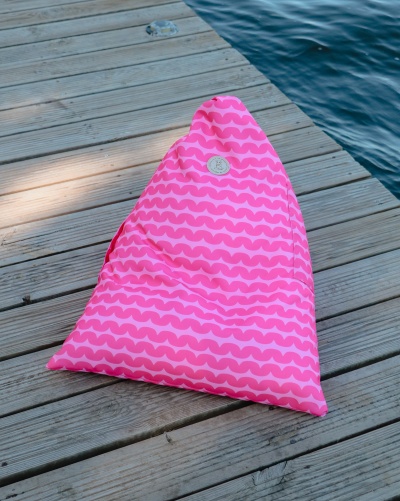 Pufe cor-de-rosa com padrão de ondas em cais de madeira junto à água