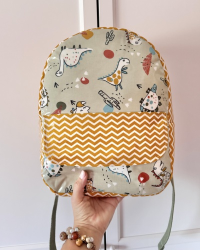 Mochila infantil com padrão de dinossauros e bolso amarelo com ziguezague