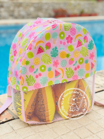 mochila colorida com padrão de frutas e bolso em rede junto a piscina
