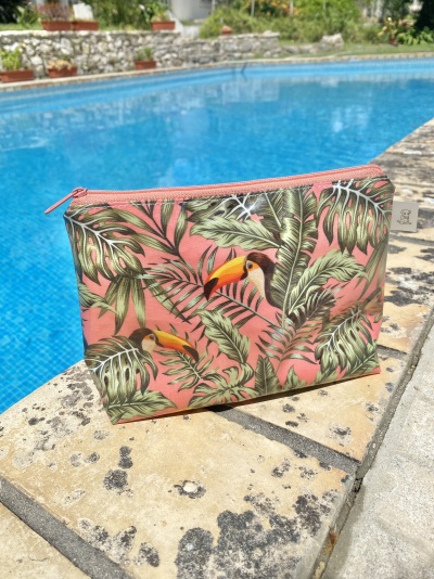 Estojo rosa com tucanos e folhas verdes ao lado de piscina