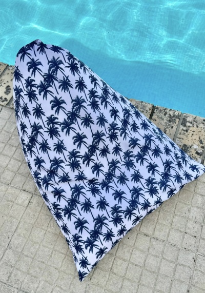 Toalha de praia branca com padrão azul de palmeiras junto a piscina