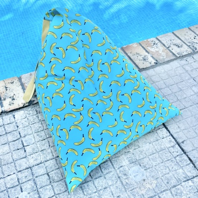Saco de tecido azul com padrão de bananas amarelas junto a piscina