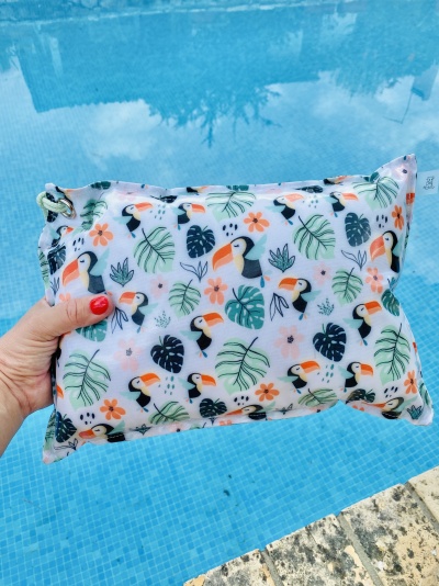 Mala branca com padrão colorido de tucanos, folhas e flores junto a piscina