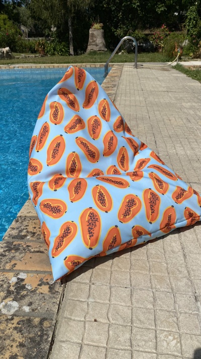 Pufe com padrão de papaias ao lado de piscina