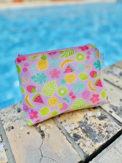 Estojo colorido com padrão de frutas junto a piscina.