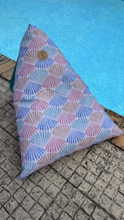 Almofada triangular colorida com padrão de conchas junto a piscina