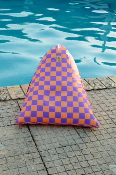 Almofada triangular laranja e roxa ao lado de piscina