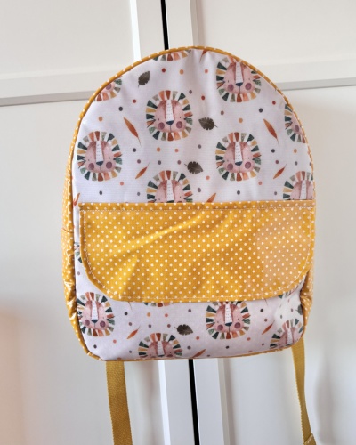 Mochila infantil com padrão de leão e bolso amarelo com bolinhas