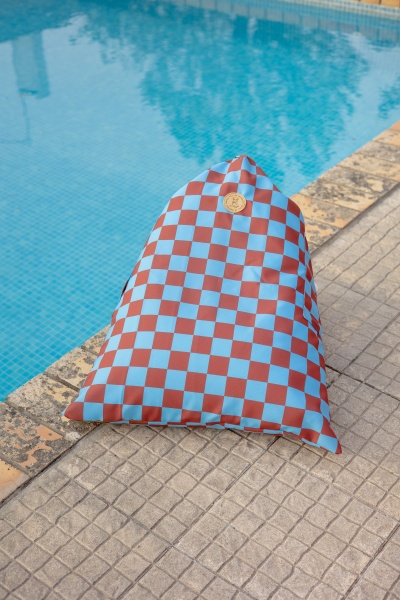 Pufe quadriculado azul claro e castanho junto a piscina com água azul
