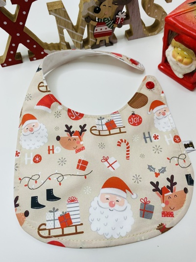 Babete natalício bege com padrão de Papai Noel e renas, fecho vermelho