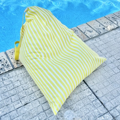 Almofada amarela com riscas brancas ao lado de uma piscina