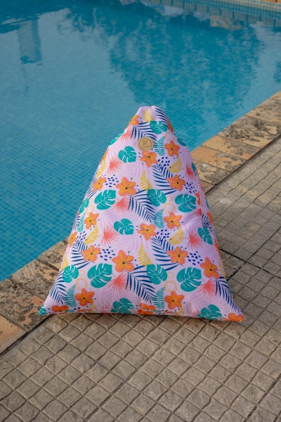 Pufe triangular com padrão floral colorido junto a piscina