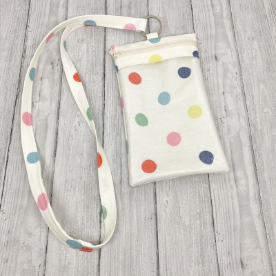 Bolsa pequena com correia e padrão de bolinhas coloridas sobre fundo claro