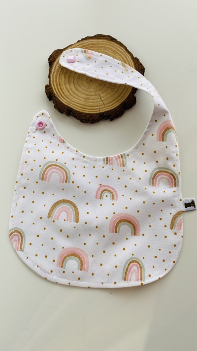 Babete branco com arcos-íris rosa e pontos cor de mostarda