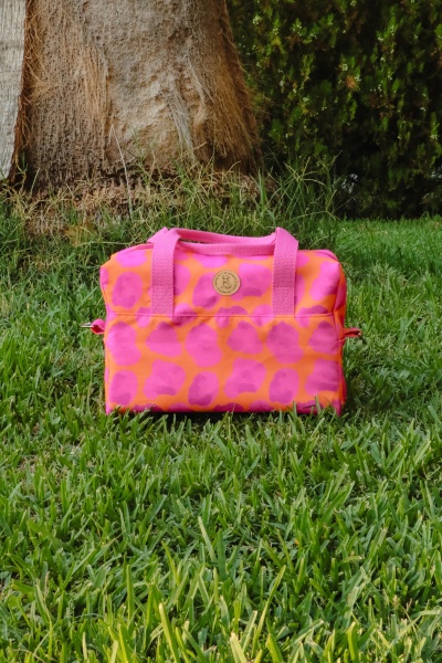 Bolsa rosa e laranja com alças cor-de-rosa sobre relva