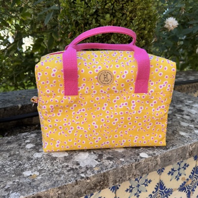 Bolsa amarela com flores rosa e brancas e alças rosa em pedra exterior