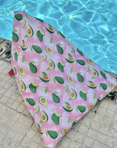 Almofada rosa com padrão de abacates perto de piscina