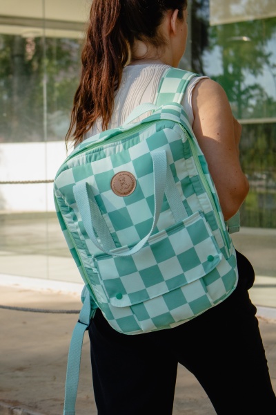 Mochila quadrada verde e branca com padrão xadrez sendo usada